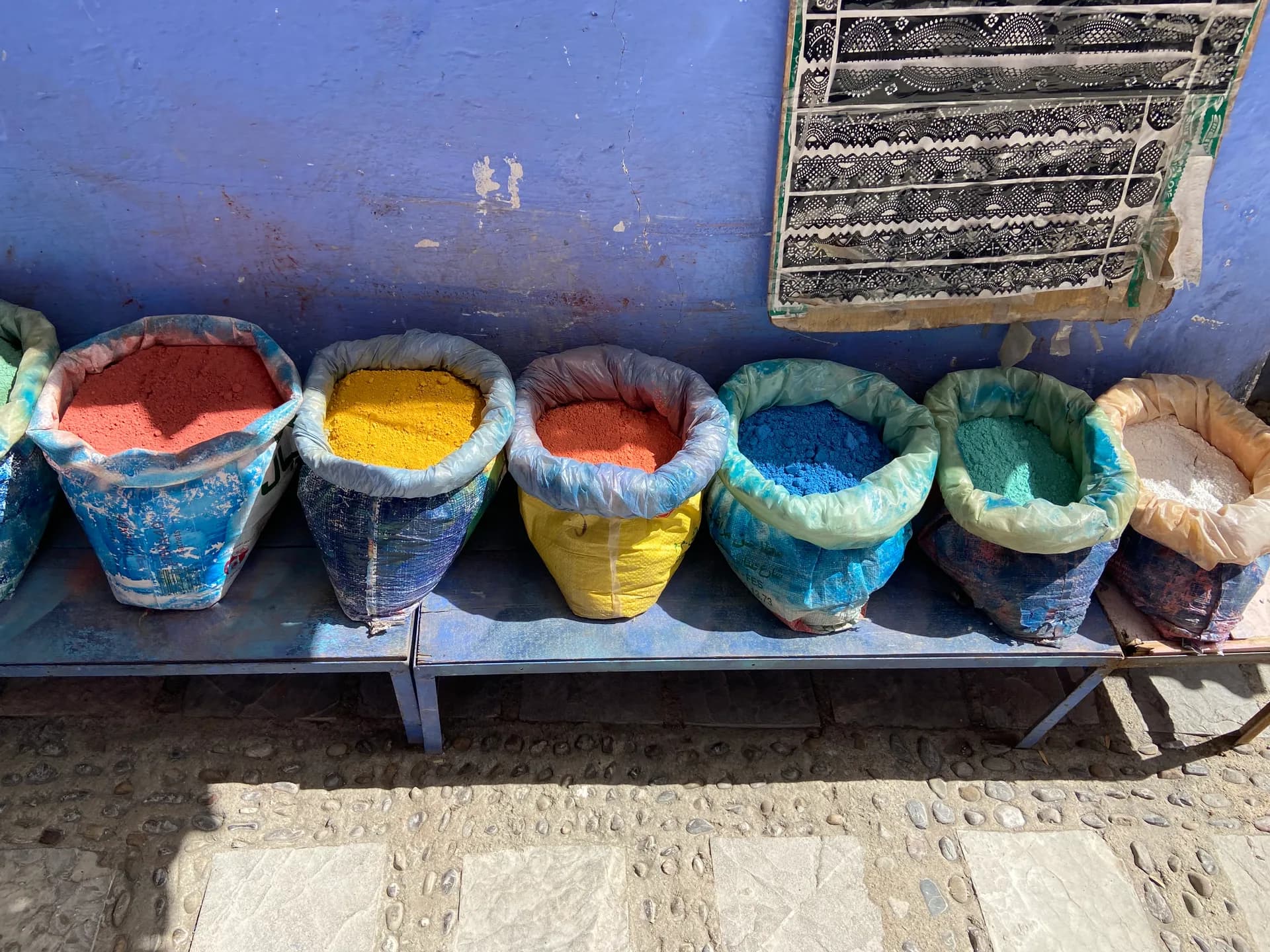 Pigments colorés au pied d’un mur bleu